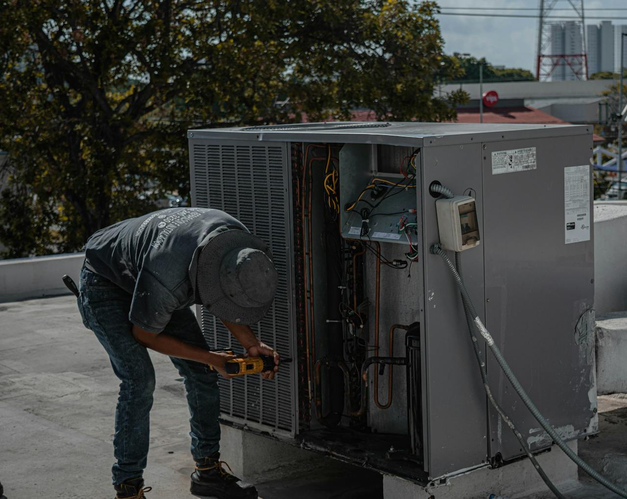 services-02 A technician is repairing an air conditioning unit on a rooftop, demonstrating skilled manual work.