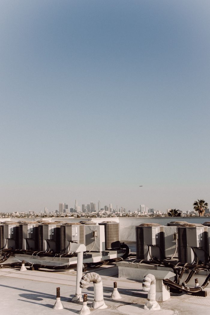 why-choose-us Rooftop HVAC units facing a distant city skyline under a clear blue sky.